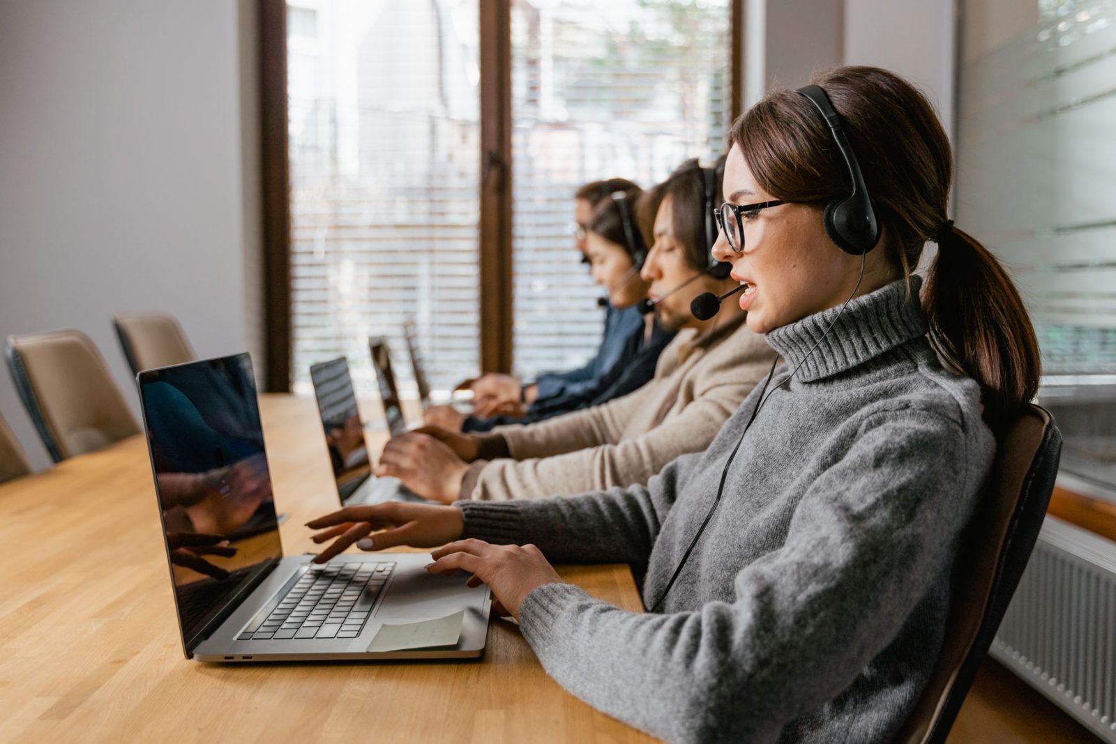 A row of coordinators working at laptops with headsets on